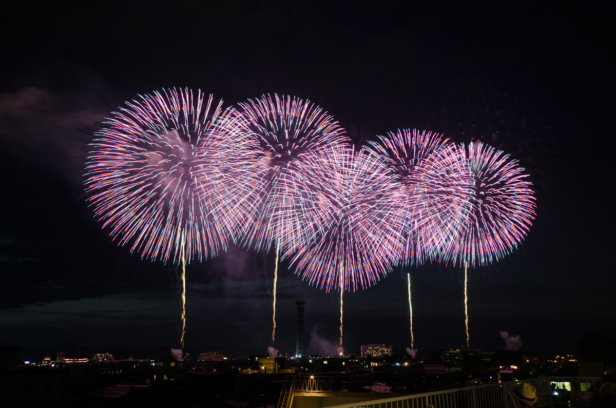 複数の花火が横方向に並んで夜空を彩る様子